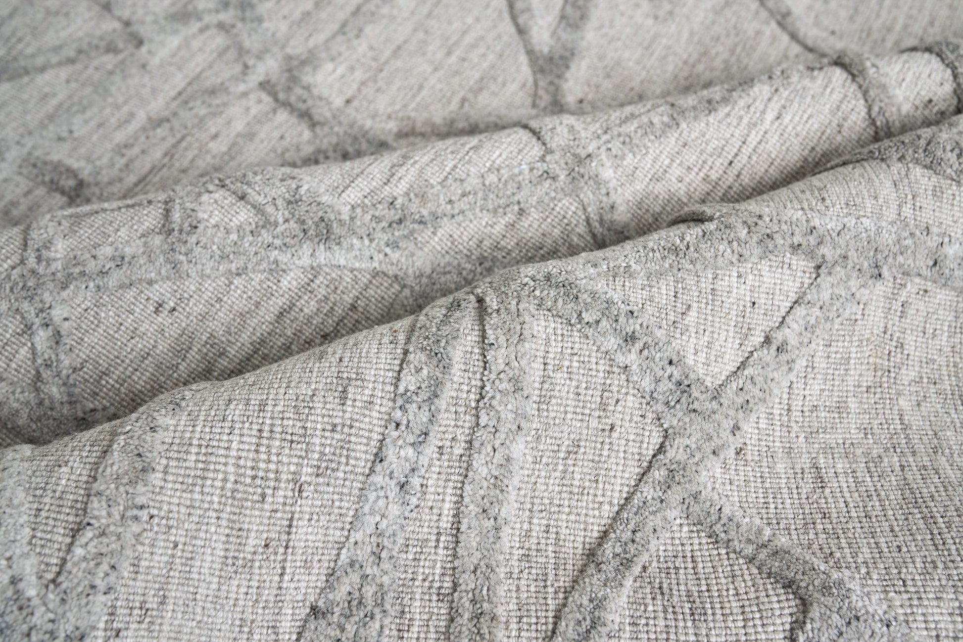 Soft grey woven fabric with a subtle geometric quilted pattern and textured weave.