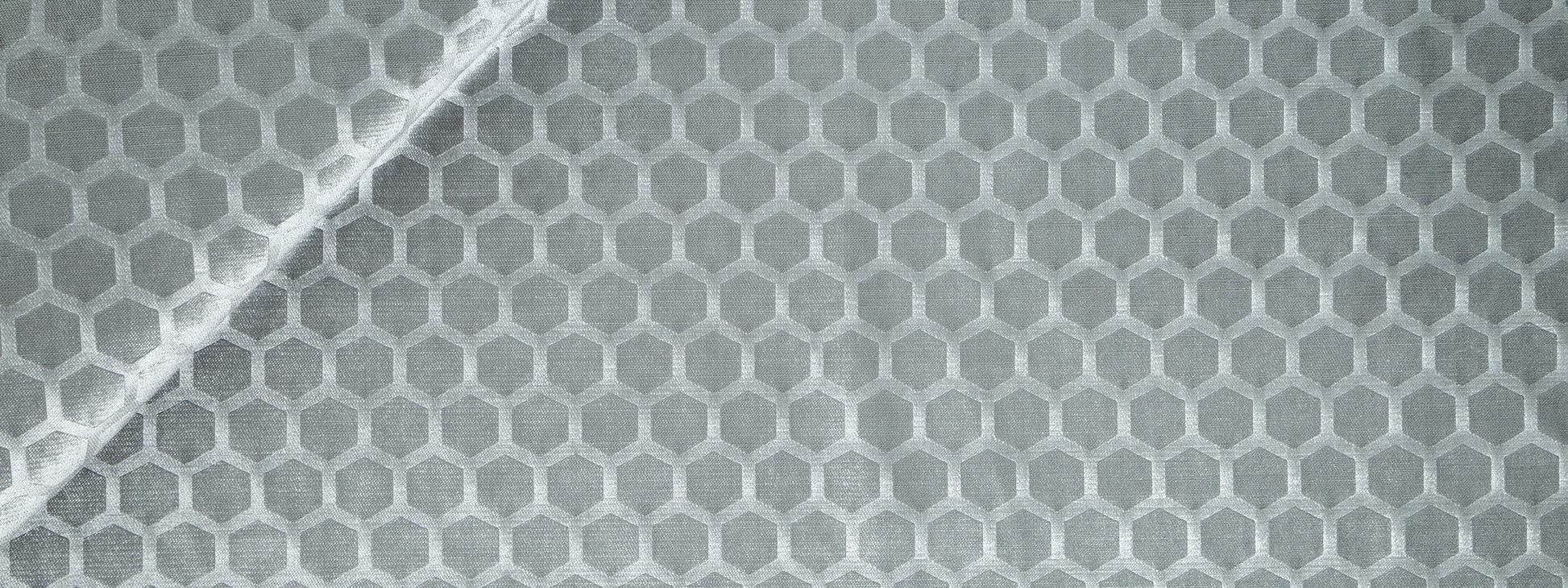 Close-up of pewter gray Soft Hex fabric with a hexagonal honeycomb pattern and a white diagonal seam.