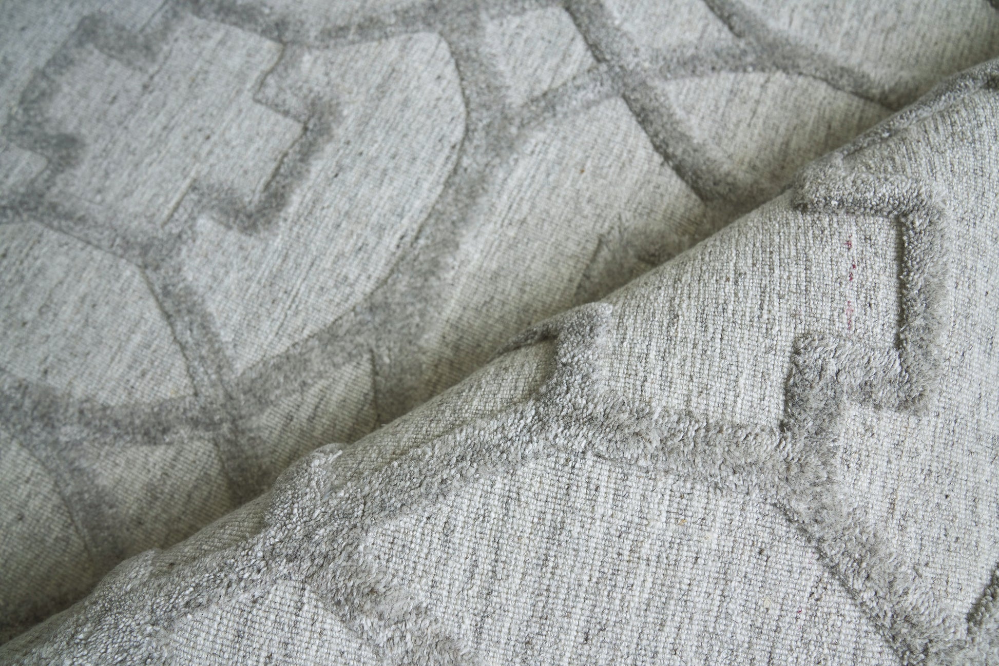 Light gray woven rug with a geometric raised pattern.
