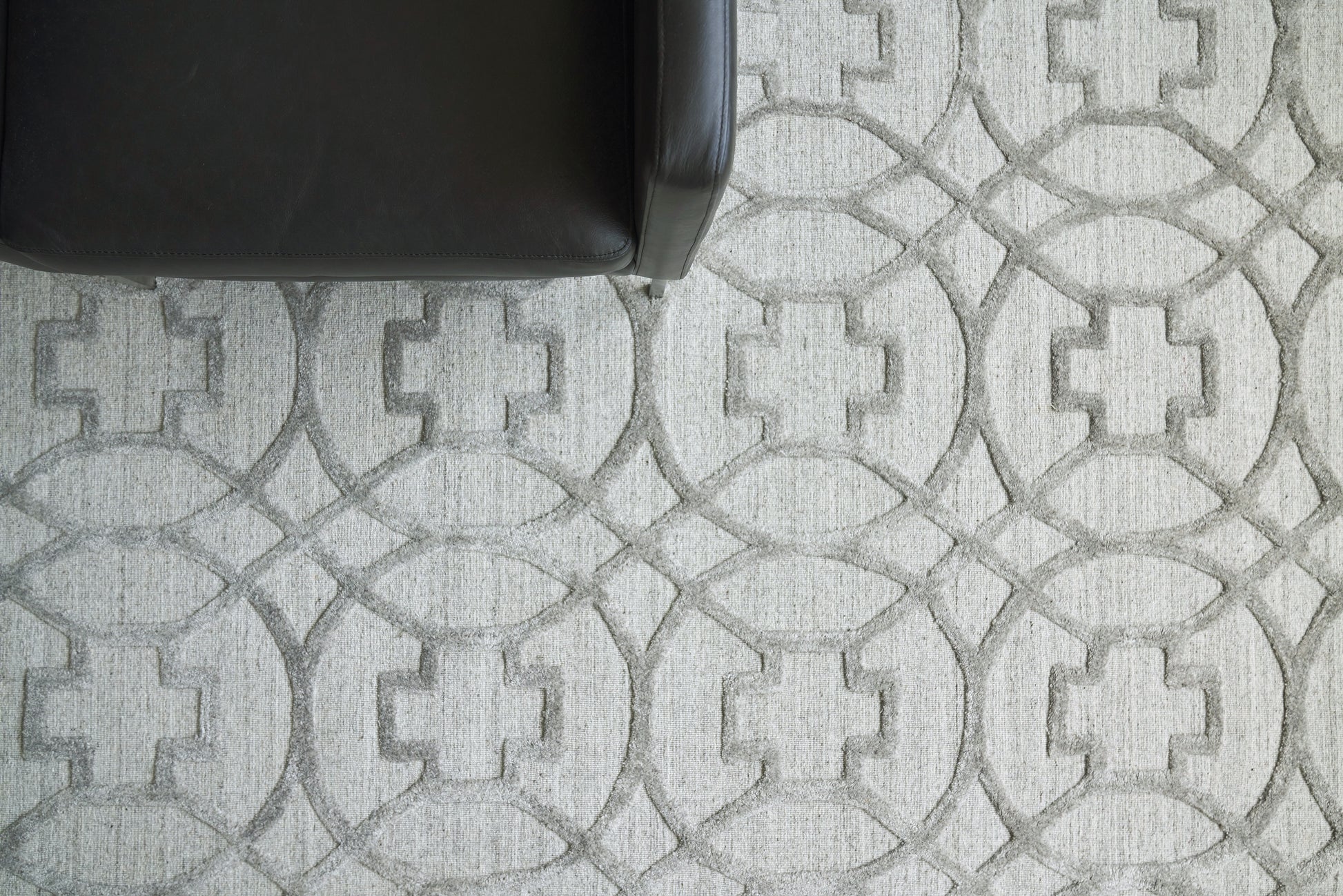 Partial view of a rug with a gray geometric pattern featuring interlocking rings.