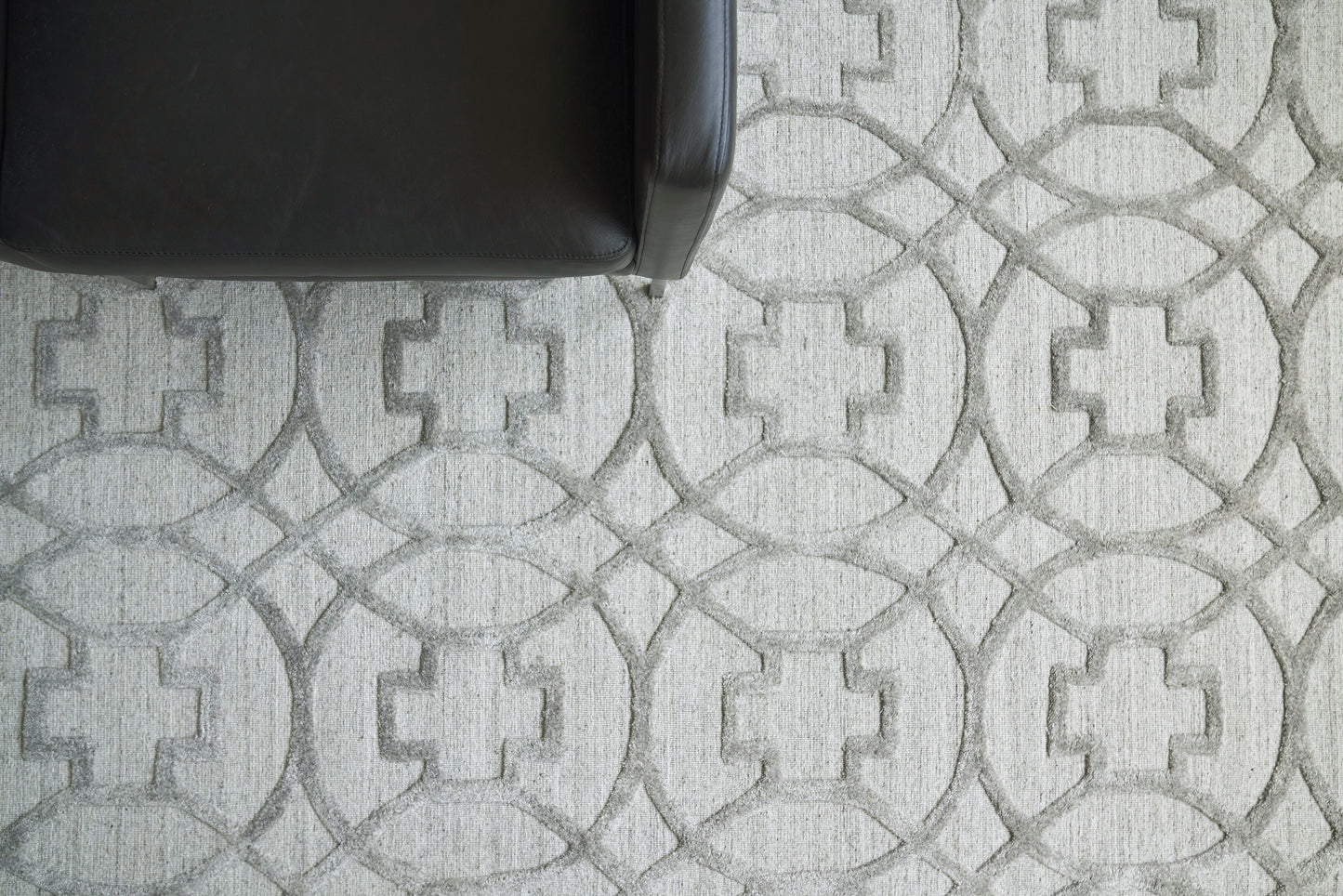 Partial view of a rug with a grayscale interlocking circular pattern, visible in the top-left corner of the image.