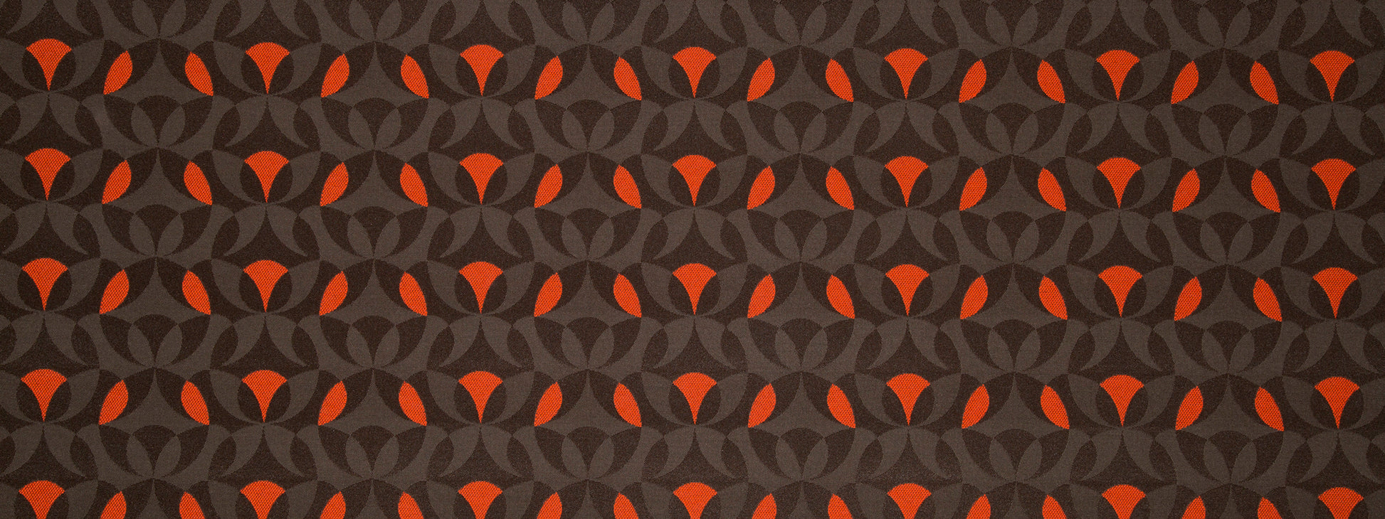 Dark charcoal gray background with an orange interlocking circular pattern; bold geometric upholstery fabric.