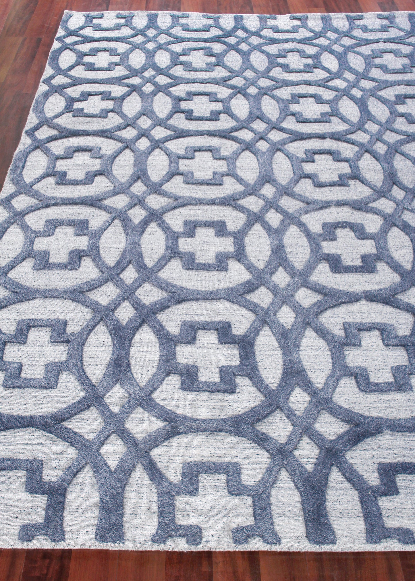 Blue and light gray geometric area rug with interlocking circles and square motifs; woven texture on a wooden floor