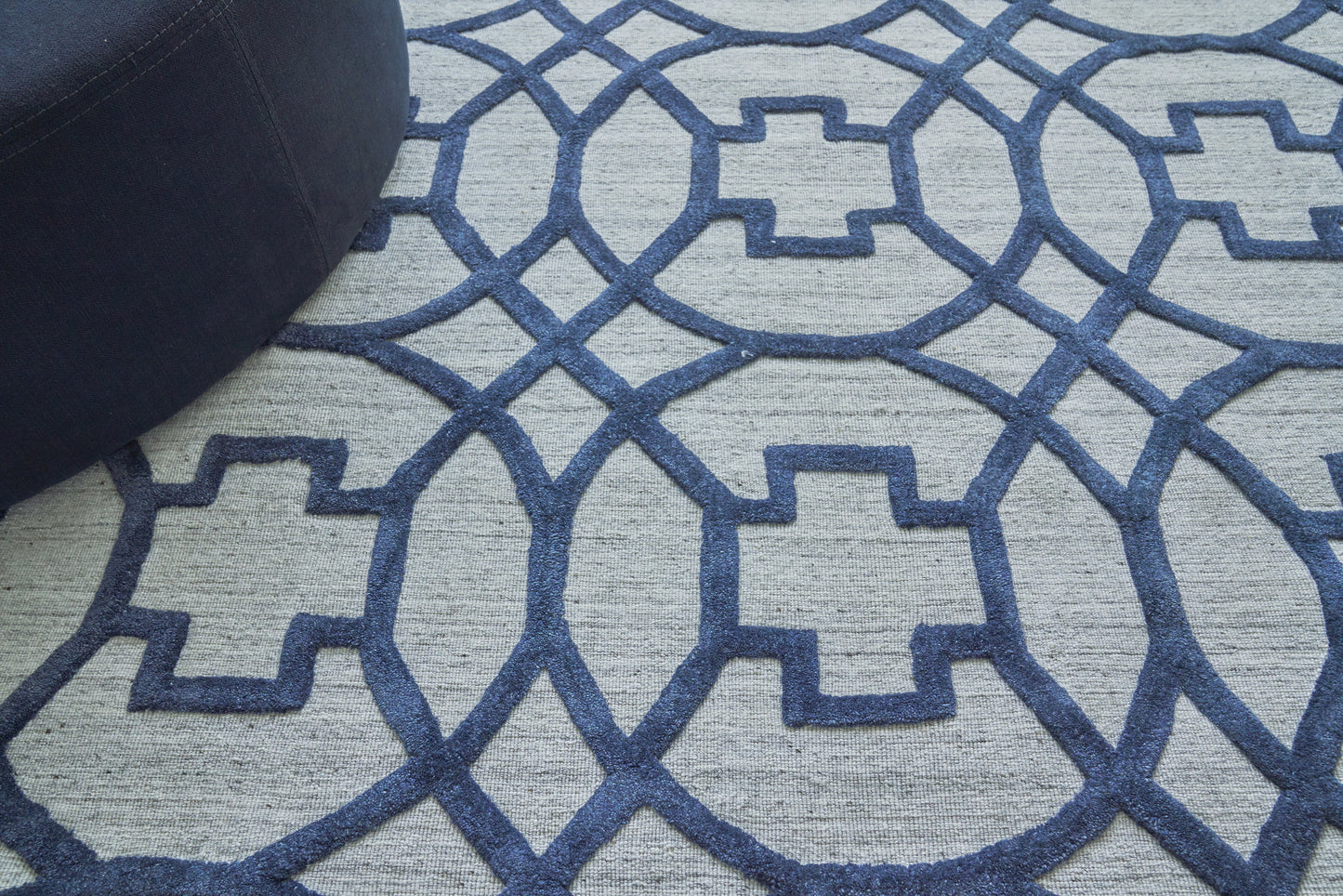 Soft light gray rug with navy blue geometric lattice pattern of interlocking circles and square motifs; modern home decor.