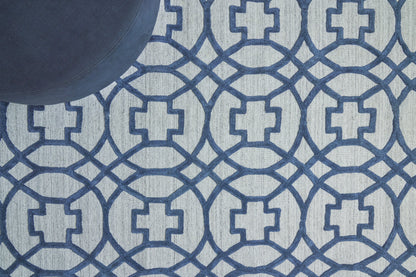 Blue geometric rug with interlocking circle-square motif; navy on light background, dark blue ball in corner.