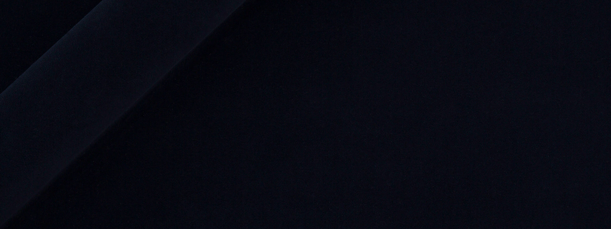 Close-up of dark navy velvet upholstery fabric with soft folds and smooth texture.