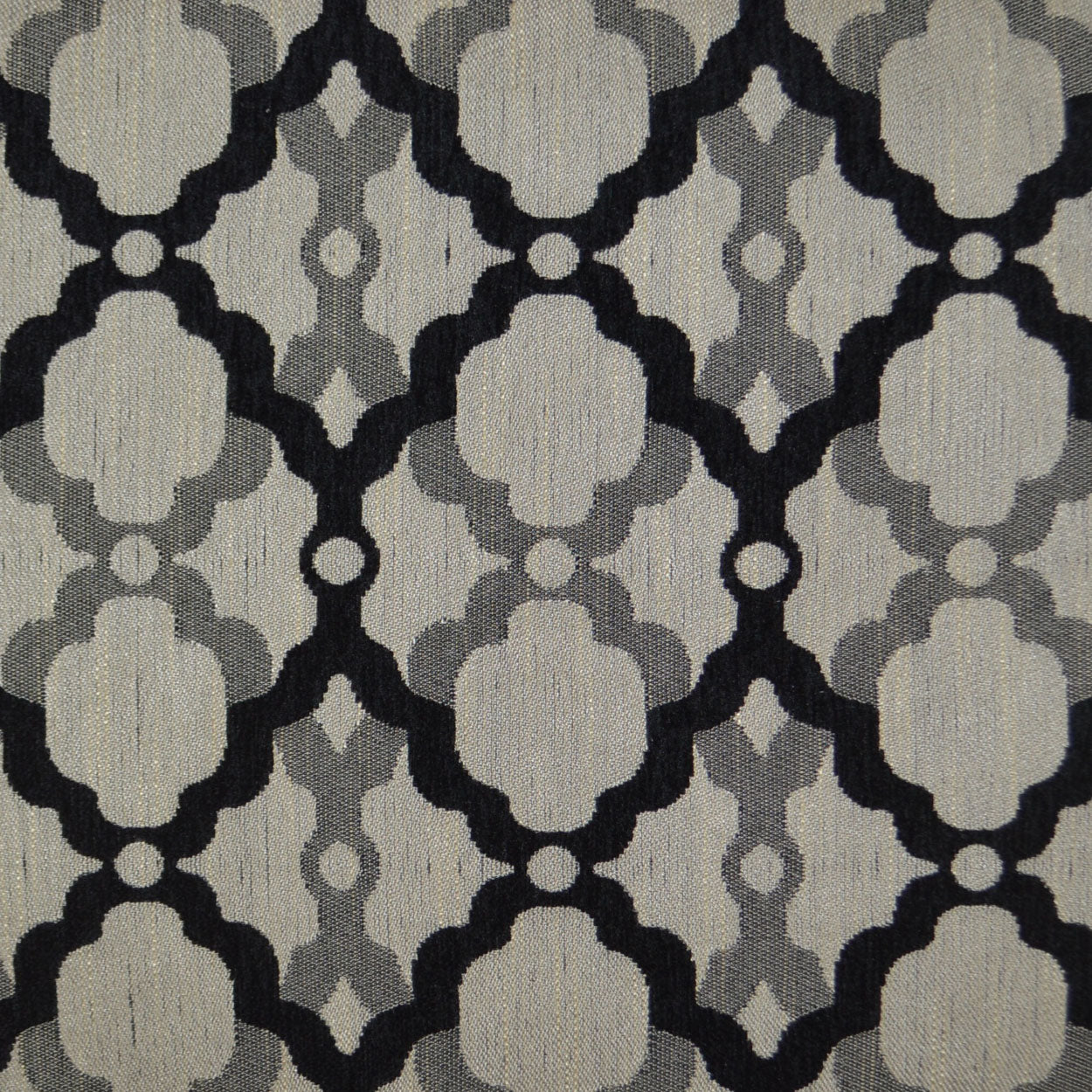 Beige woven pillow (24 x 24 in) with a repeating black and gray quatrefoil trellis pattern.