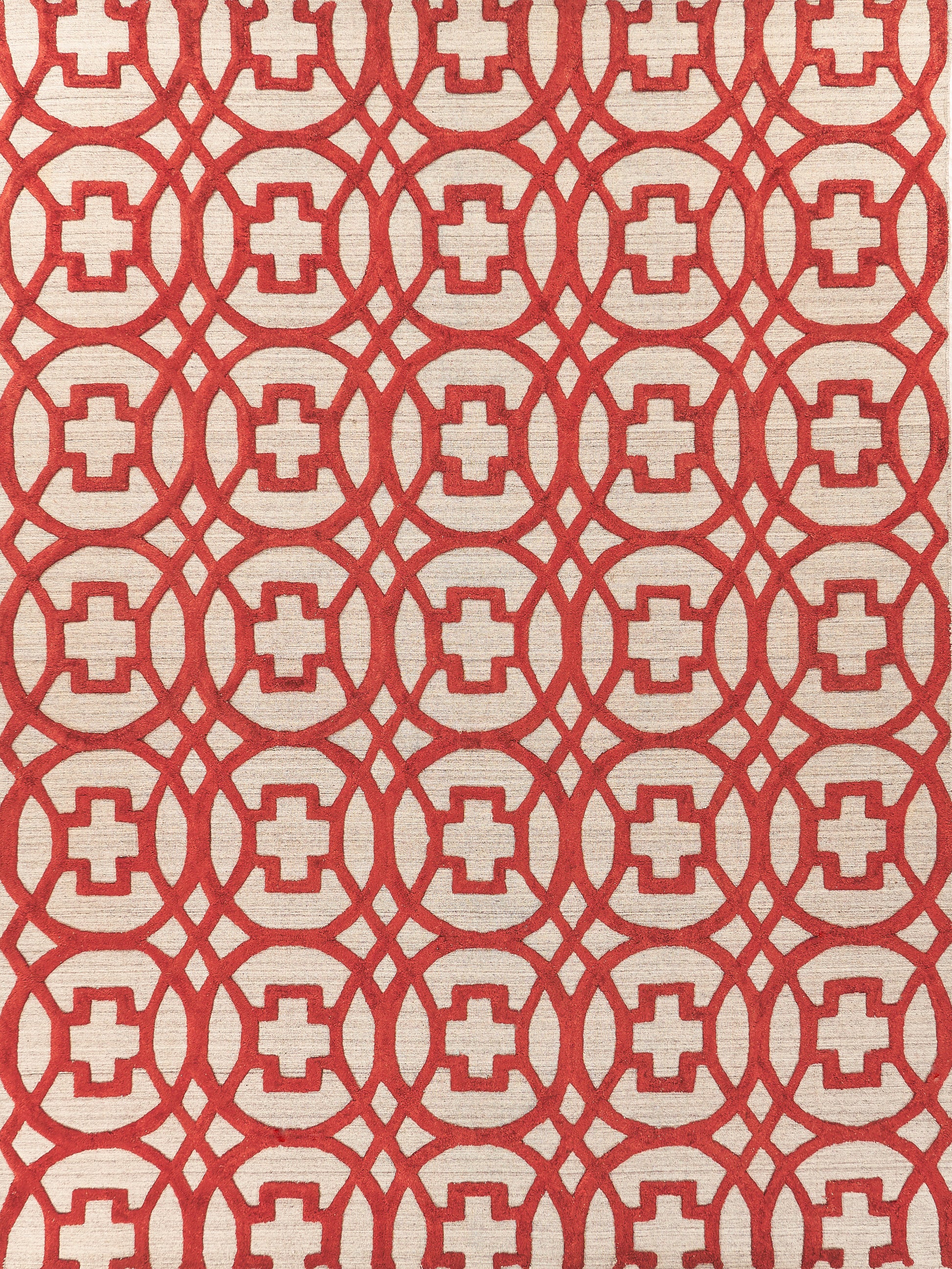 Red geometric lattice on beige rug; circular rings with square centers forming a bold repeating pattern.