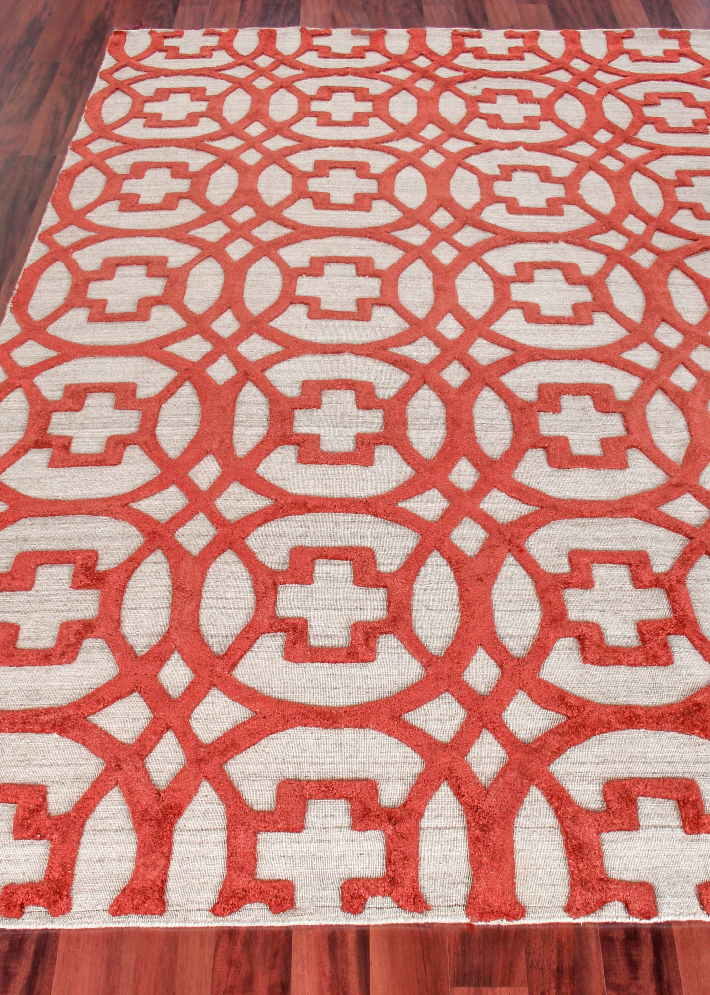 Rectangular area rug with bold red geometric lattice and circular motifs on a cream background; modern oriental style.