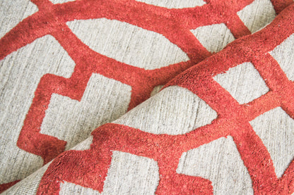 Red geometric lattice pattern on light gray woven rug.