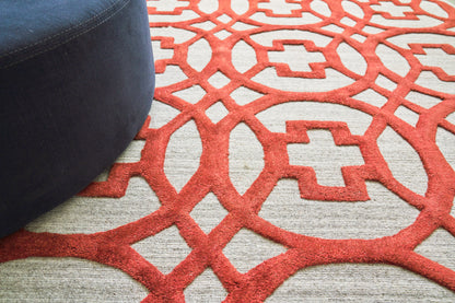 Navy rug featuring a bold red geometric lattice pattern on a gray field.