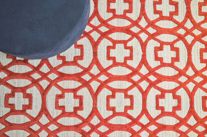 Red geometric lattice rug with white cross motifs on a light background; blue round cushion at top-left.
