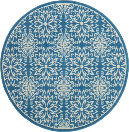 Round blue rug with white intricate floral snowflake motif and teal border.