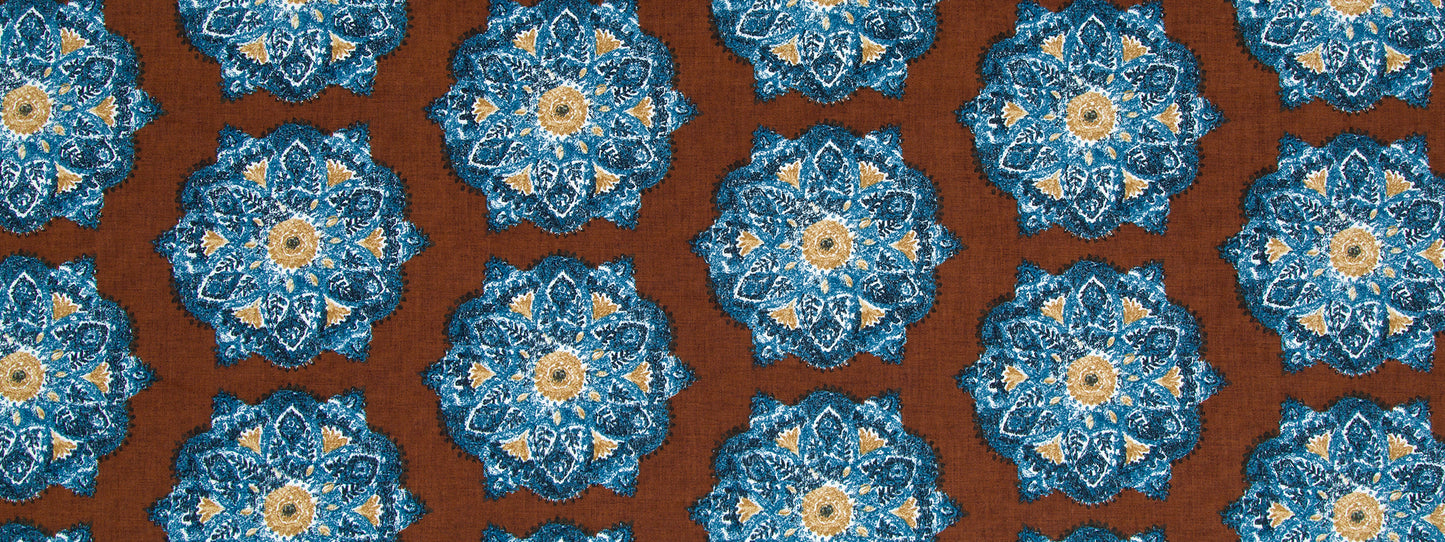 Repeating floral medallion motifs in cognac tones on a warm brown background; intricate textile pattern.