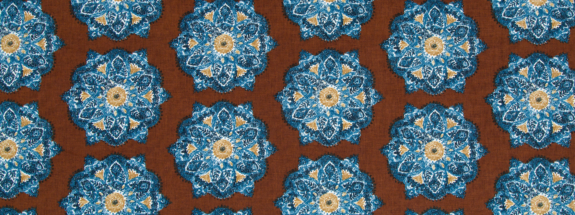 Repeating floral medallion motifs in cognac tones on a warm brown background; intricate textile pattern.