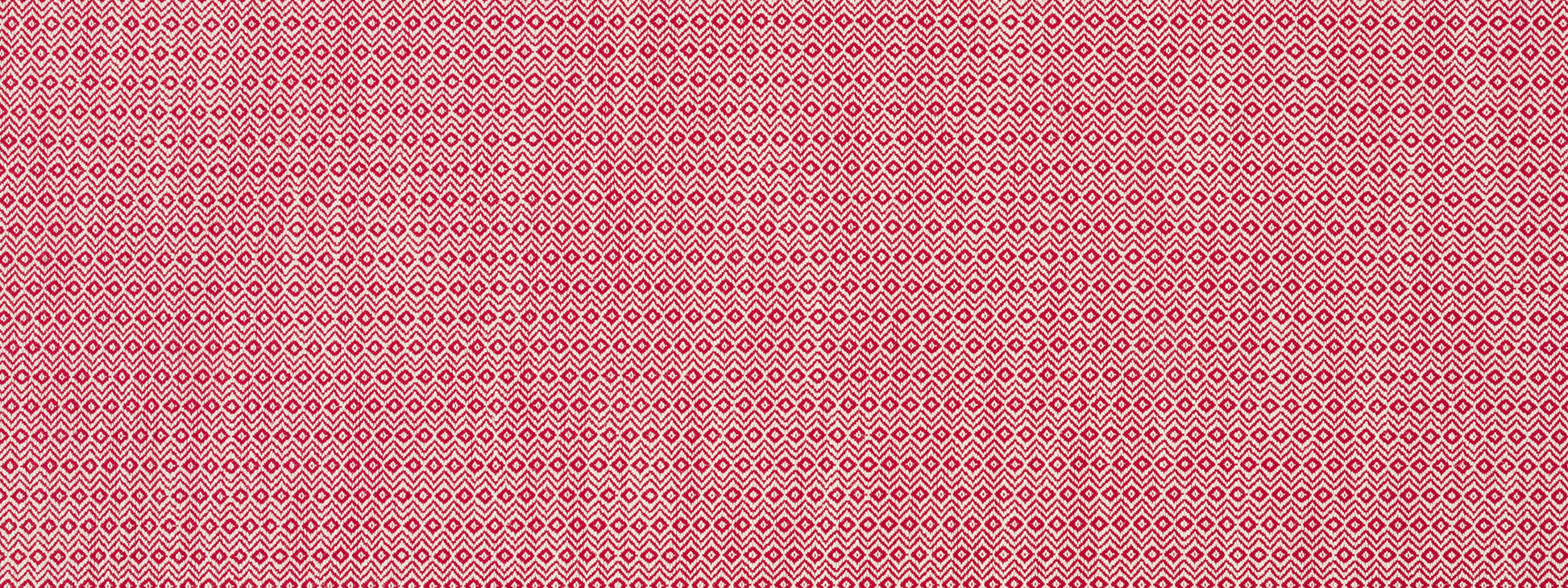 Pink upholstery fabric with tiny white diamond-shaped motifs in a repeating geometric pattern; a soft woven textile.