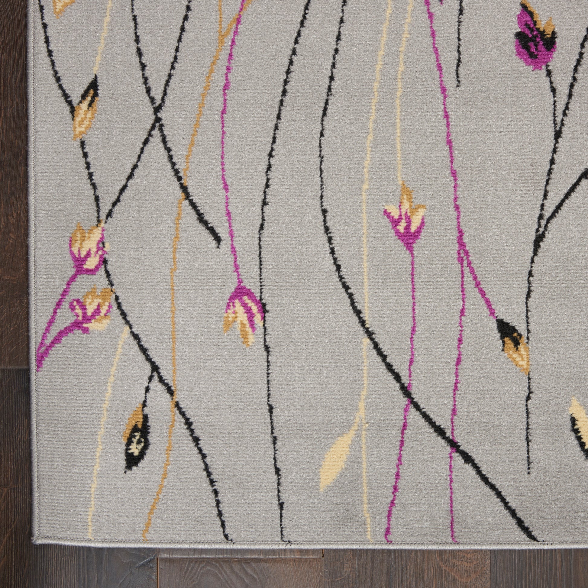 Abstract floral area rug on gray field with black and magenta wavy lines, yellow accents, small flowers, light border.