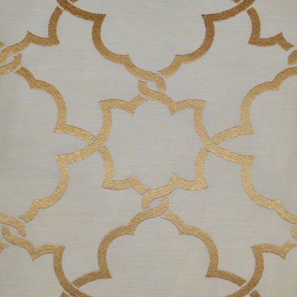 Beige pillow with gold metallic interlocking quatrefoil trellis pattern.
