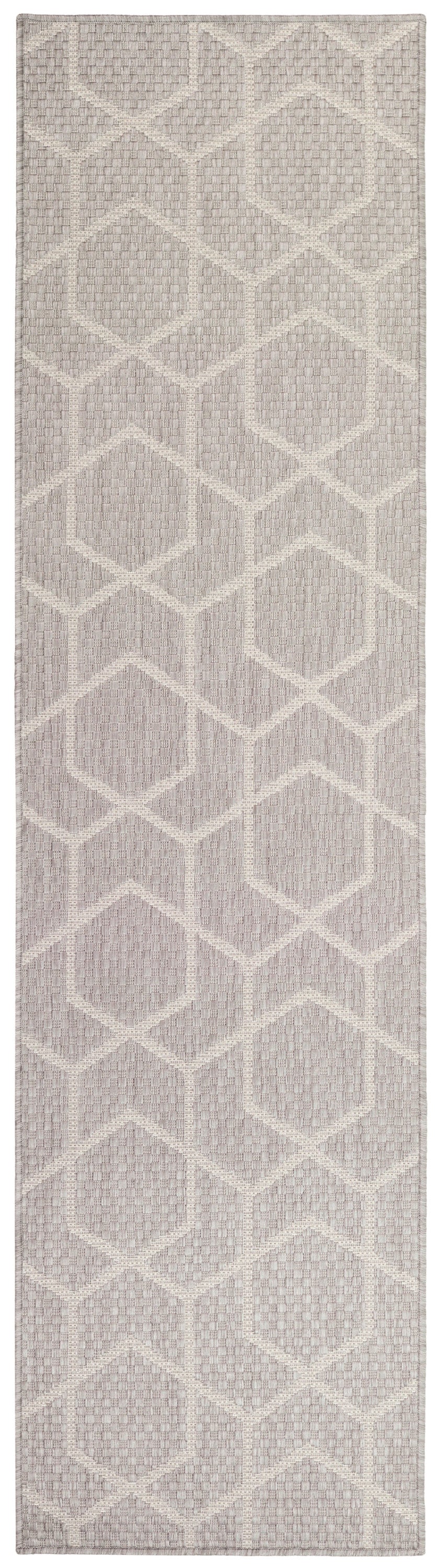 Textured flatweave runner rug with ivory geometric hexagon pattern on dusty taupe-lavender background.
