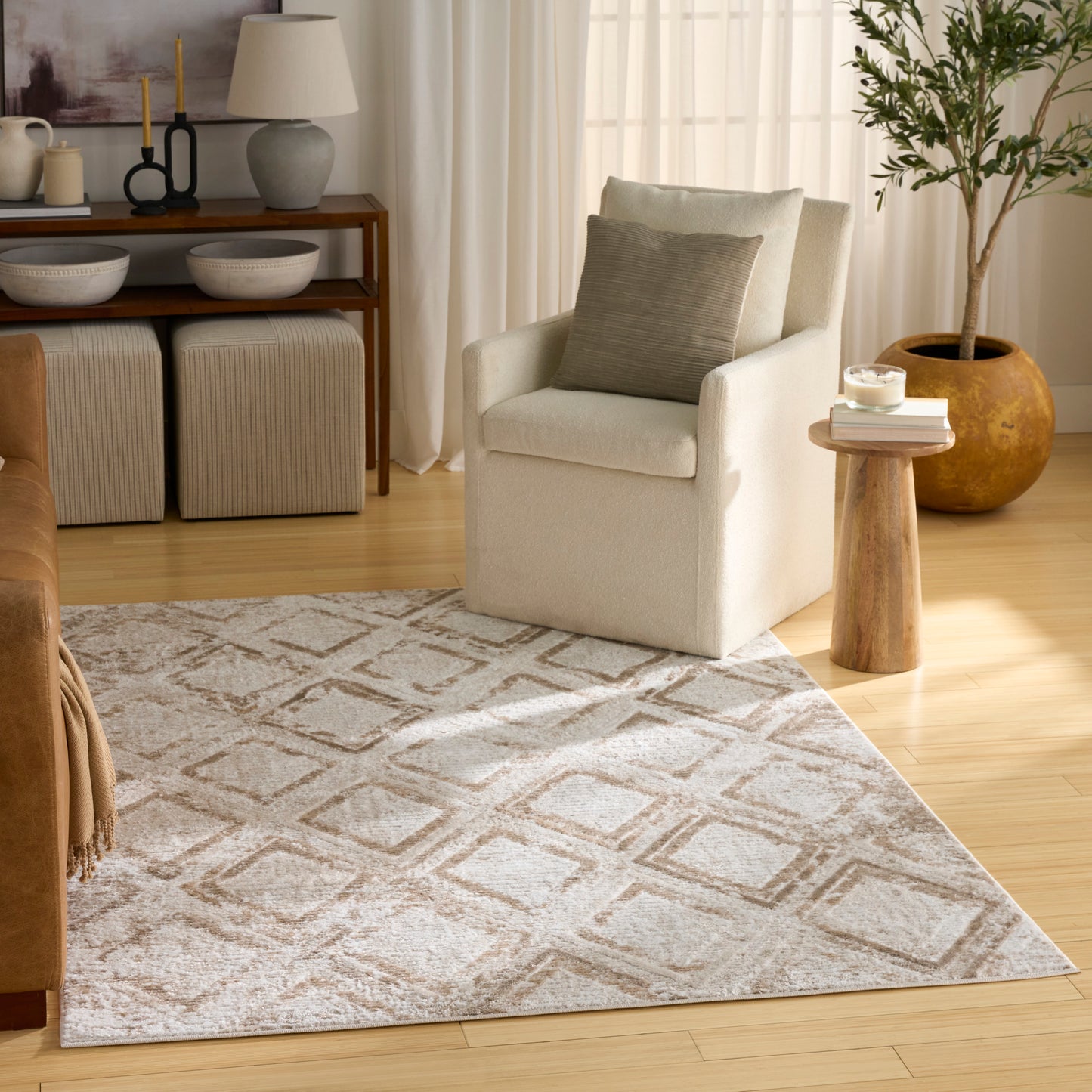 Soft cream area rug with taupe geometric diamond pattern in a cozy living room setting.