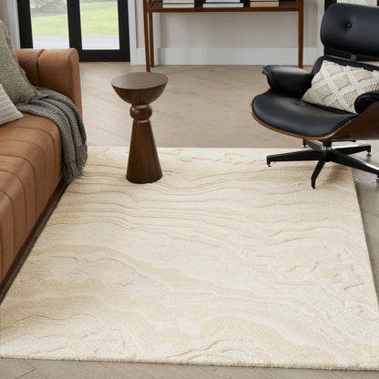 Cream area rug with subtle, wavy pattern; tan sofa, wooden side table, and black lounge chair in a bright living room.