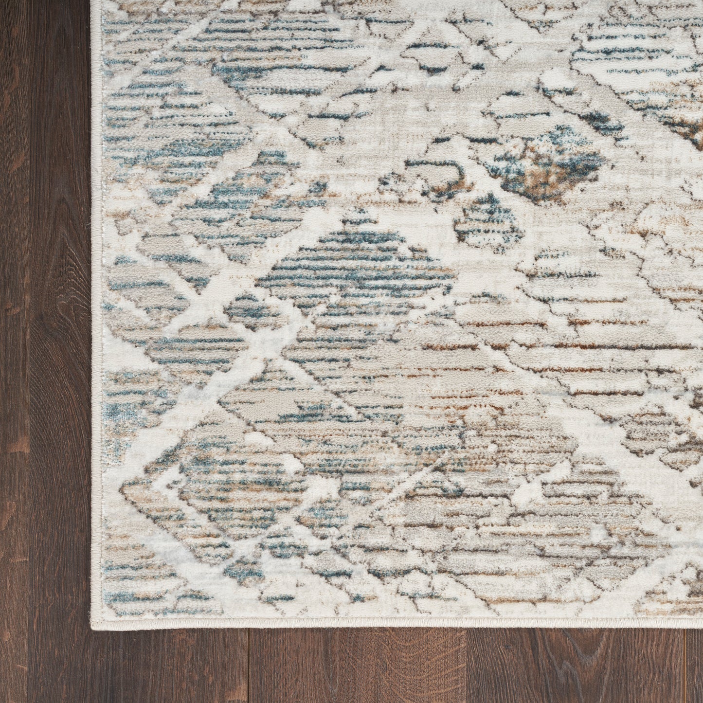 Rectangular distressed geometric runner rug in cream, blue, and gray with diamond motif on dark wood floor.