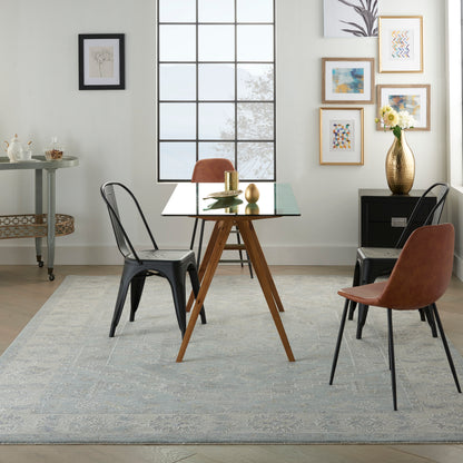 Vintage-style rug (8' x 10') in a dining room setting under a glass-top table with wooden tripod legs and metal chairs.