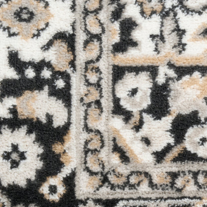 Close-up of a cream, black and tan oriental rug with floral motifs and a bordered edge, plush pile.