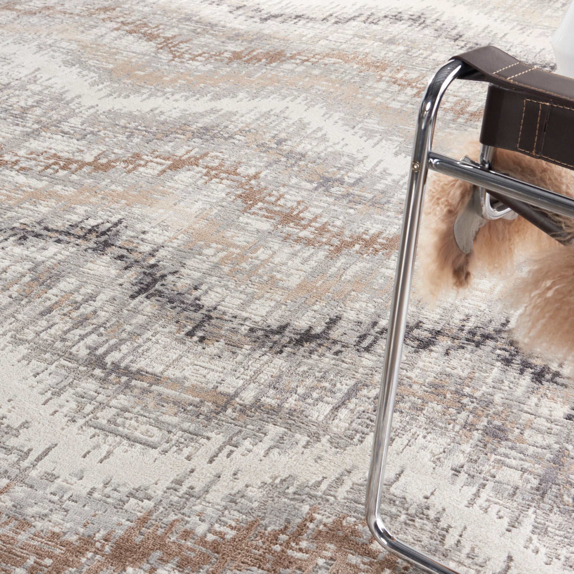 Beige-gray patterned rug with a chrome curved-frame chair featuring a brown leather seat.