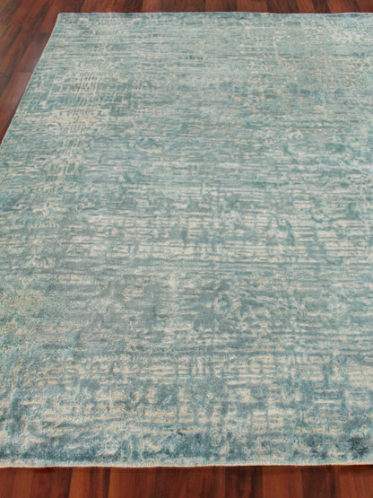 Teal blue distressed-pattern rectangular area rug on wood floor, soft textured look.