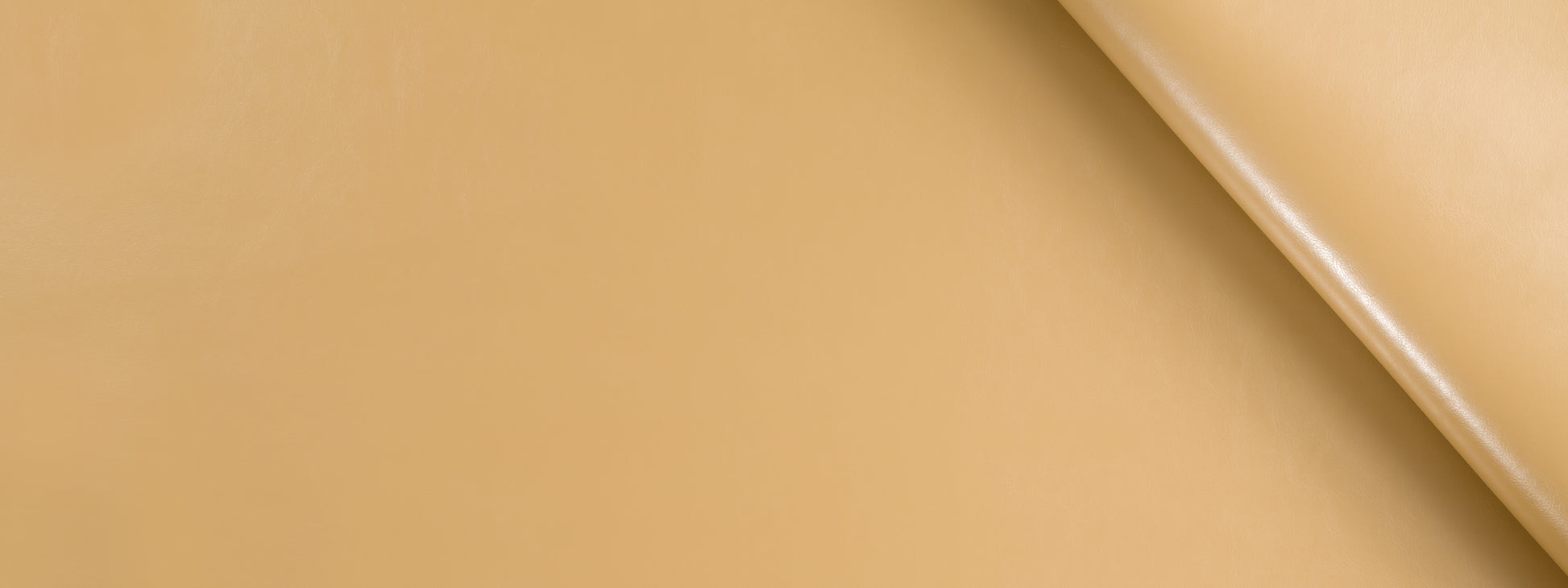 Tan leather texture with a diagonal seam and curved edge; smooth, premium upholstery leather.