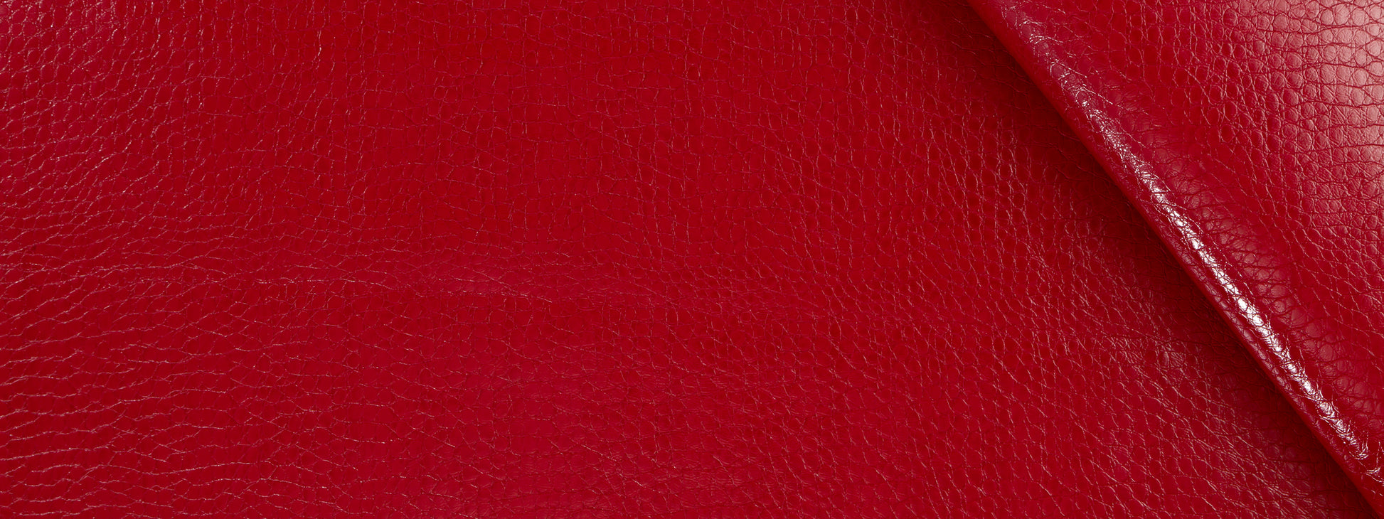 Close-up red crocodile-textured upholstery with a diagonal stitched edge.