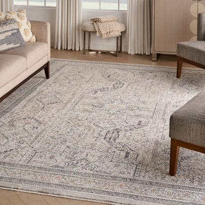 Neutral area rug with a geometric medallion pattern in ivory and gray, woven texture, in a cozy living room with beige sofa.
