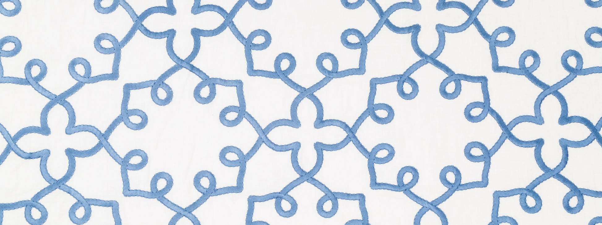 Blue embroidered looped scroll pattern on white fabric; decorative textile with stitched lattice design.