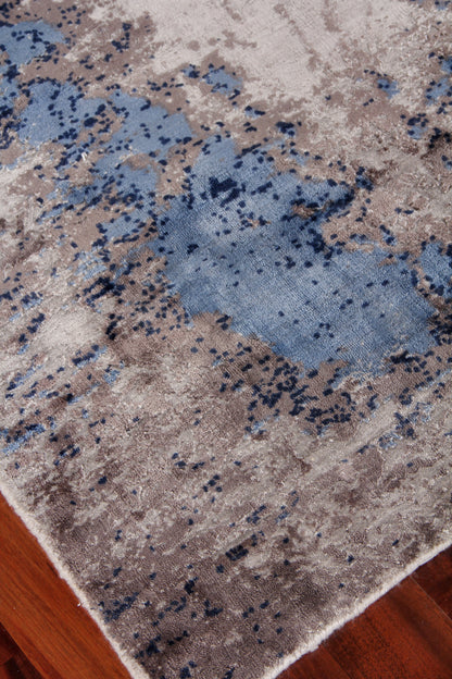 Rectangular abstract area rug with blue, gray, and tan blotches on beige background; plush modern distressed style.