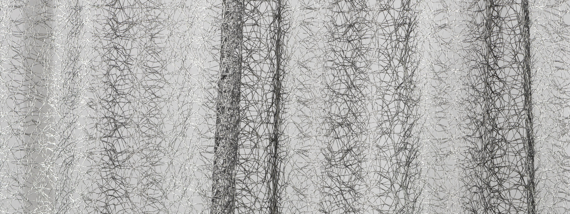 Silver metallic sheer curtain fabric with crinkled texture and vertical folds, adds modern shimmer to windows.