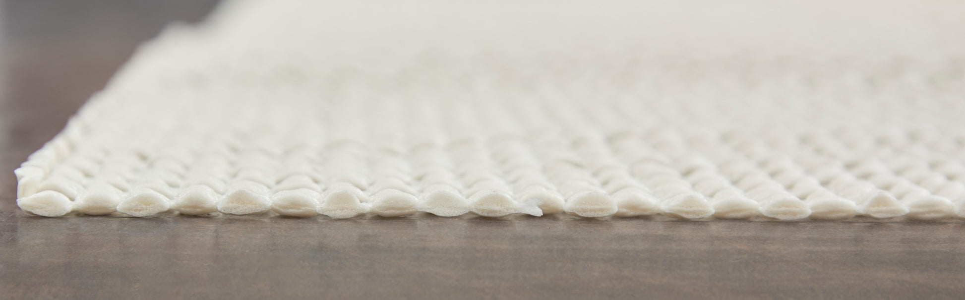 White looped-texture rug, 5' x 8', with soft rounded tufts and a low-pile, on a wooden floor.