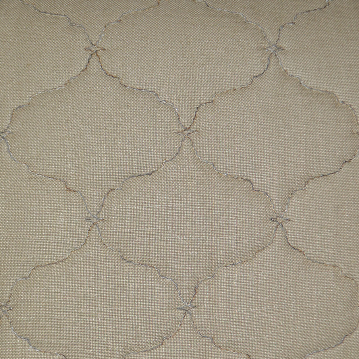 Beige fabric with subtle stitched quatrefoil motif in cream thread; quilted, textured home textile.
