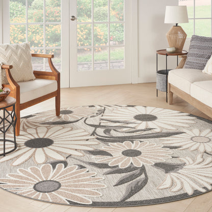 Round woven rug with oversized beige and gray daisy flowers, neutral tones, ideal for living rooms.