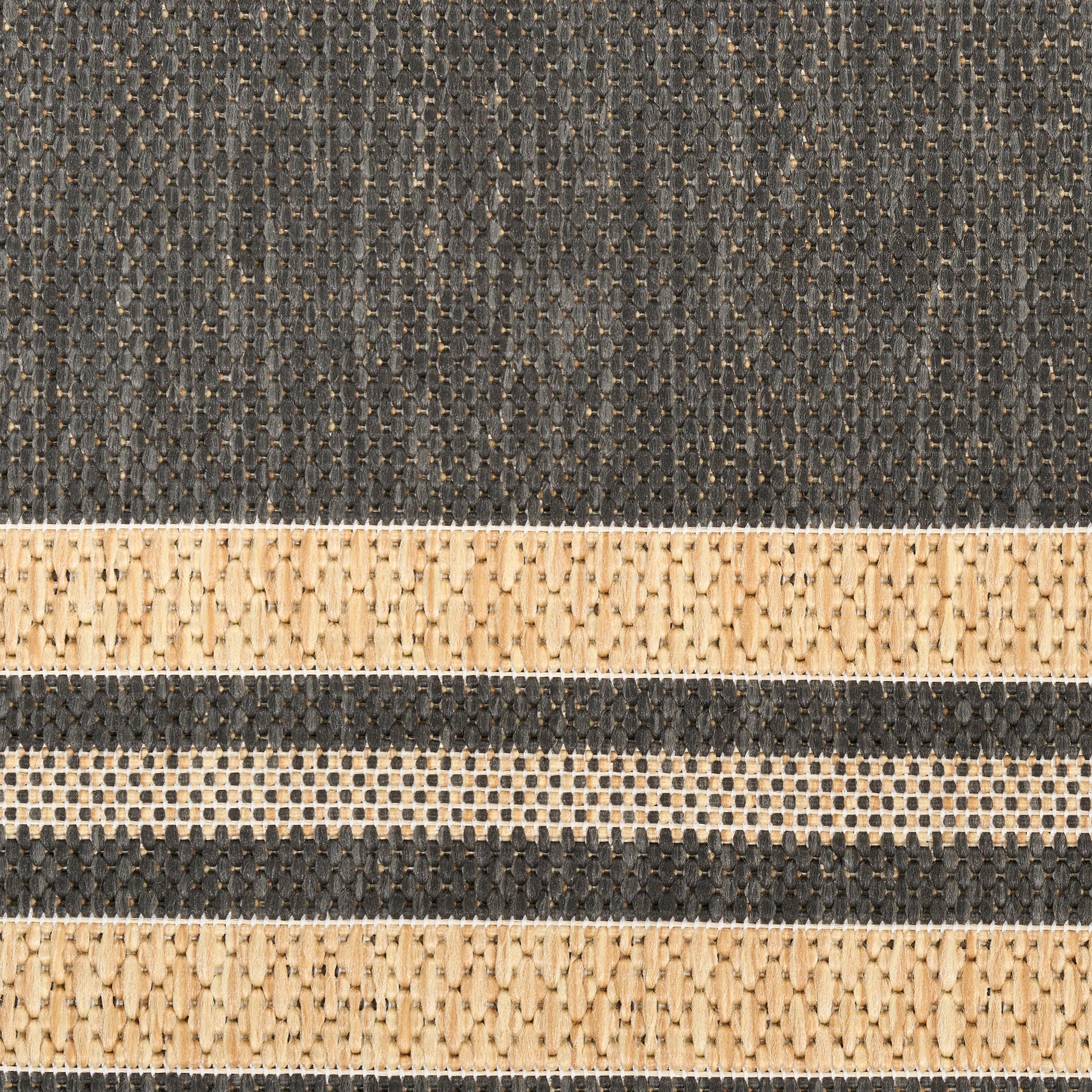 Close-up of a dark charcoal woven rug with natural beige stripe bands and textured jute fibers.