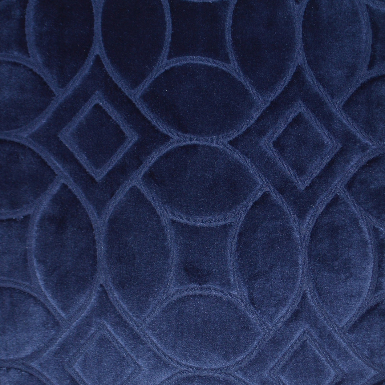 Deep blue velvet fabric with a raised geometric pattern of interlocking circles and diamonds; luxe upholstery.