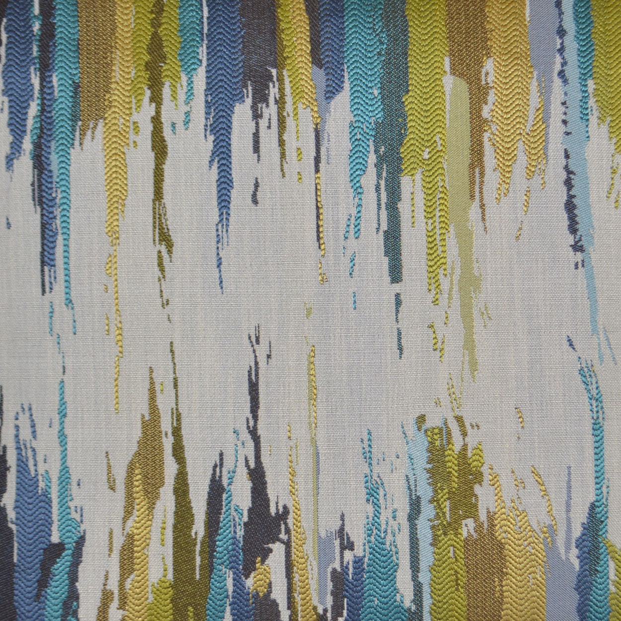 Pillow featuring vertical abstract brushstrokes in blue, teal, yellow, olive and gray on a light beige background.