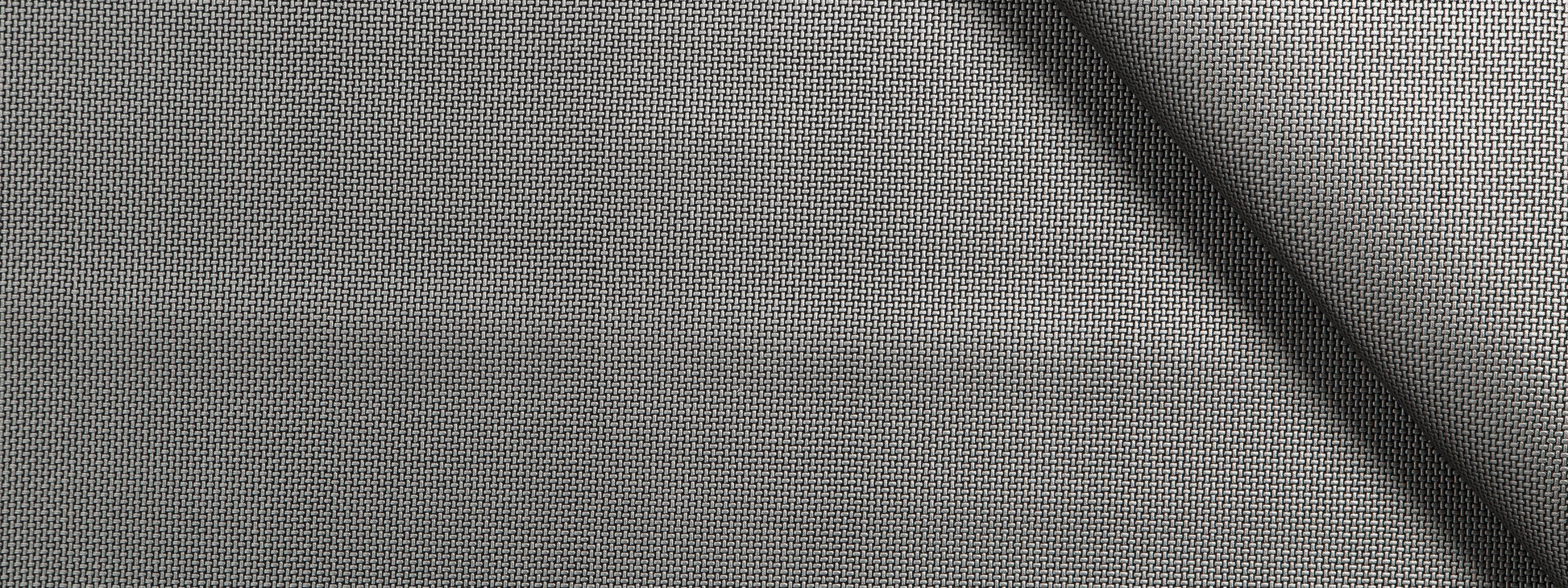 Close-up of gray woven fabric with fine grid texture and a diagonal seam.