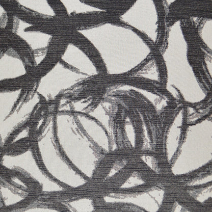 Abstract pattern of black and dark gray interlocking circles on a light gray textured pillow.