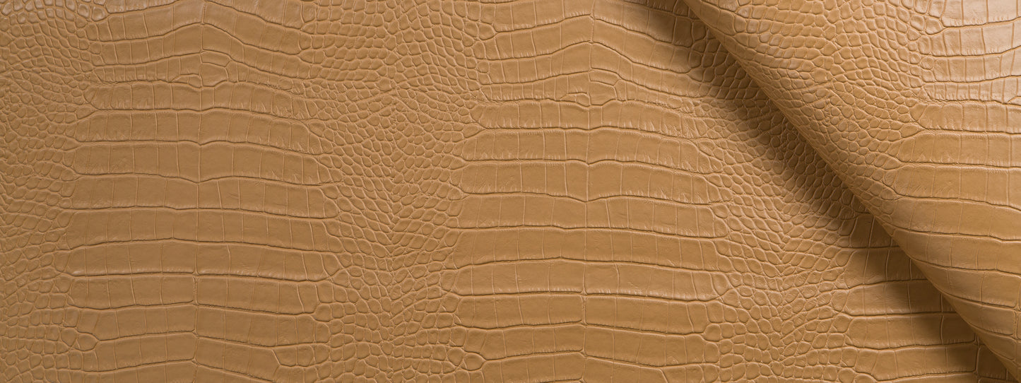 Camel crocodile-embossed upholstery fabric close-up with reptile-scale pattern.