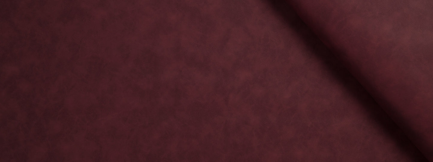 Close-up of burgundy velvet fabric with soft nap and a diagonal fold.
