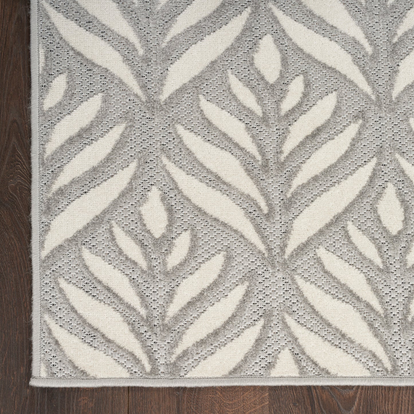 Rectangular gray and ivory woven rug with cream leaf pattern and subtle border, modern botanical design.