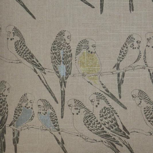 Beige fabric with a budgie print in blue, yellow, and gray perched on branches.