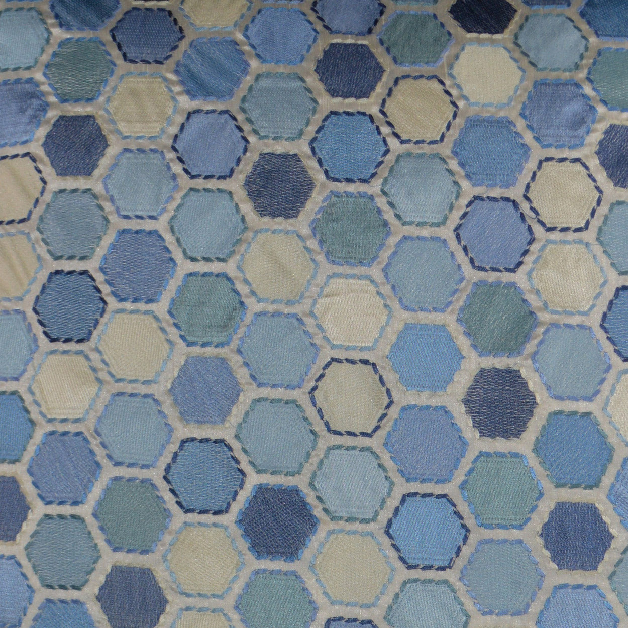 Hexagon-patterned blue fabric with cream outlines on a quilted pillow.