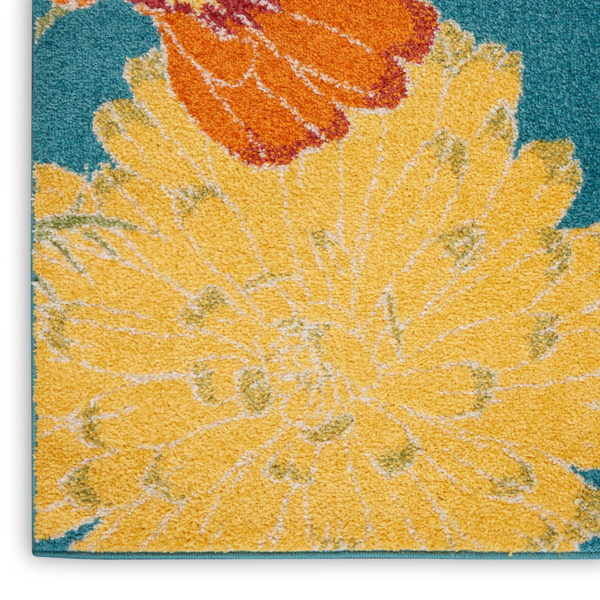 Close-up of a textured floral rug with a large yellow bloom and orange accents on teal background.